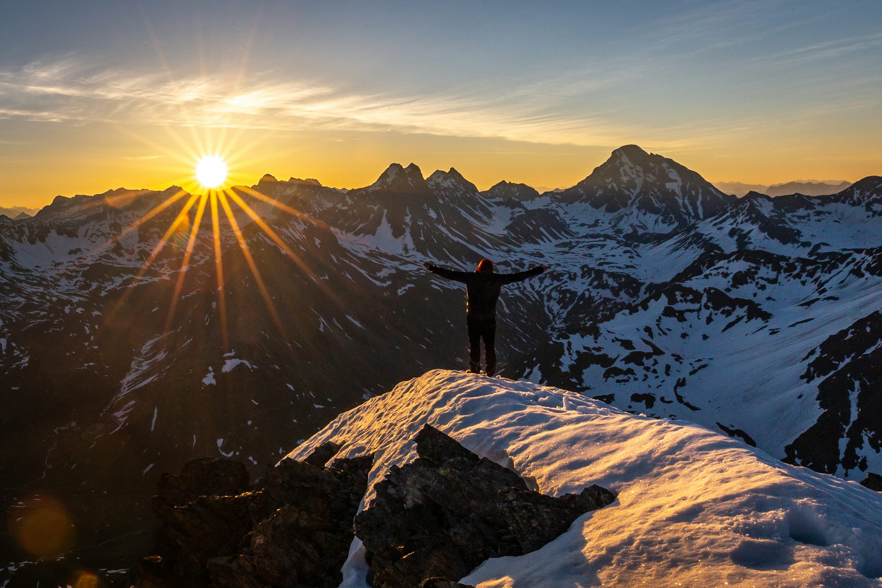 Person standing on hilltop overlooking vast landscape at sunrise